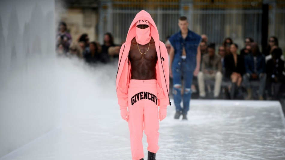 El hombre Givenchy lleva capucha, torso desnudo y botas de lluvia